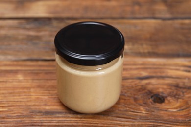 Tasty nut paste in jar on wooden table, closeup