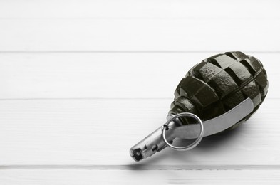 Photo of Hand grenade on white wooden table, closeup. Space for text