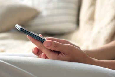 Photo of Young woman with smartphone on sofa, closeup