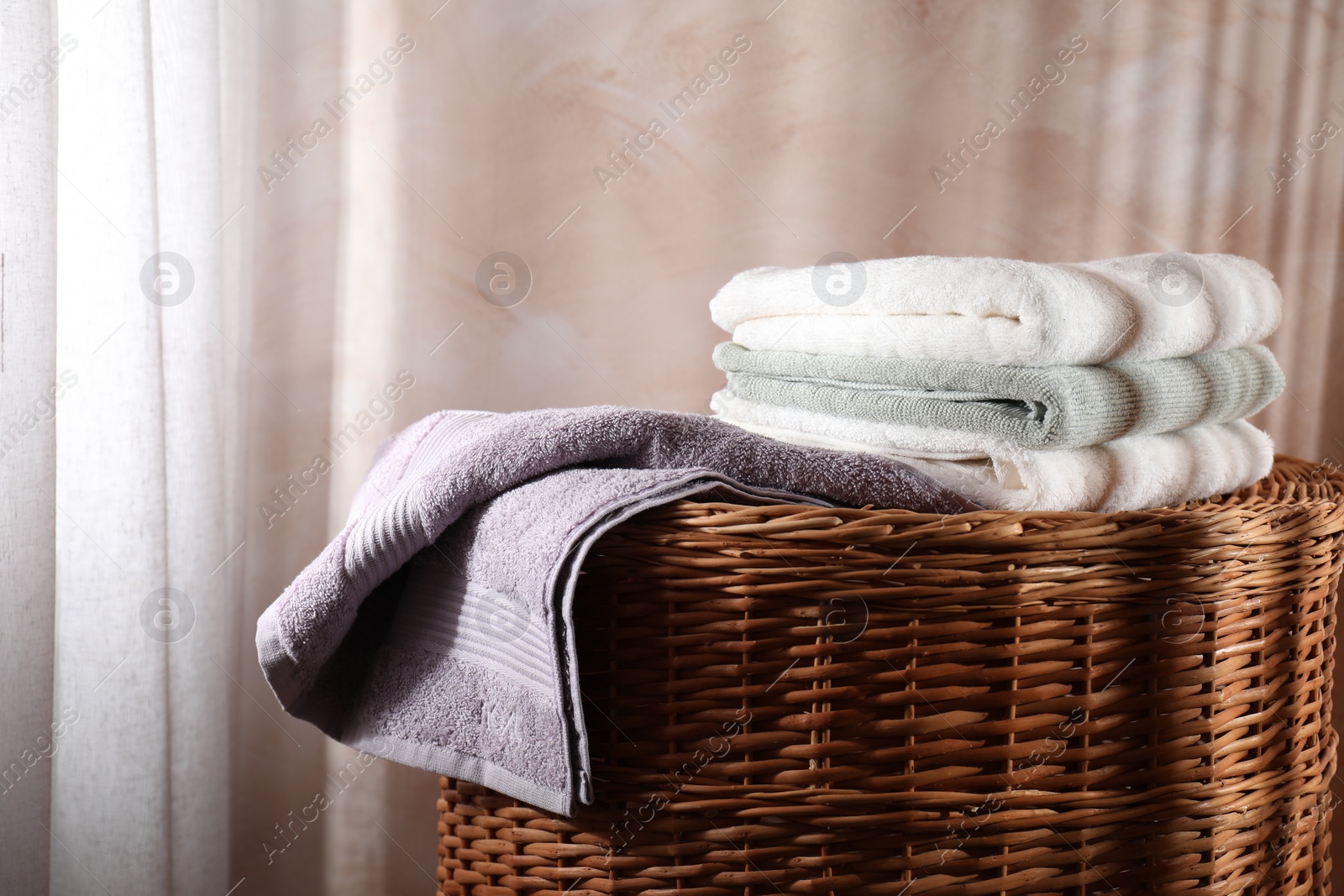Photo of Stacked soft towels on rattan laundry basket indoors
