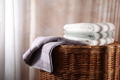 Stacked soft towels on rattan laundry basket indoors