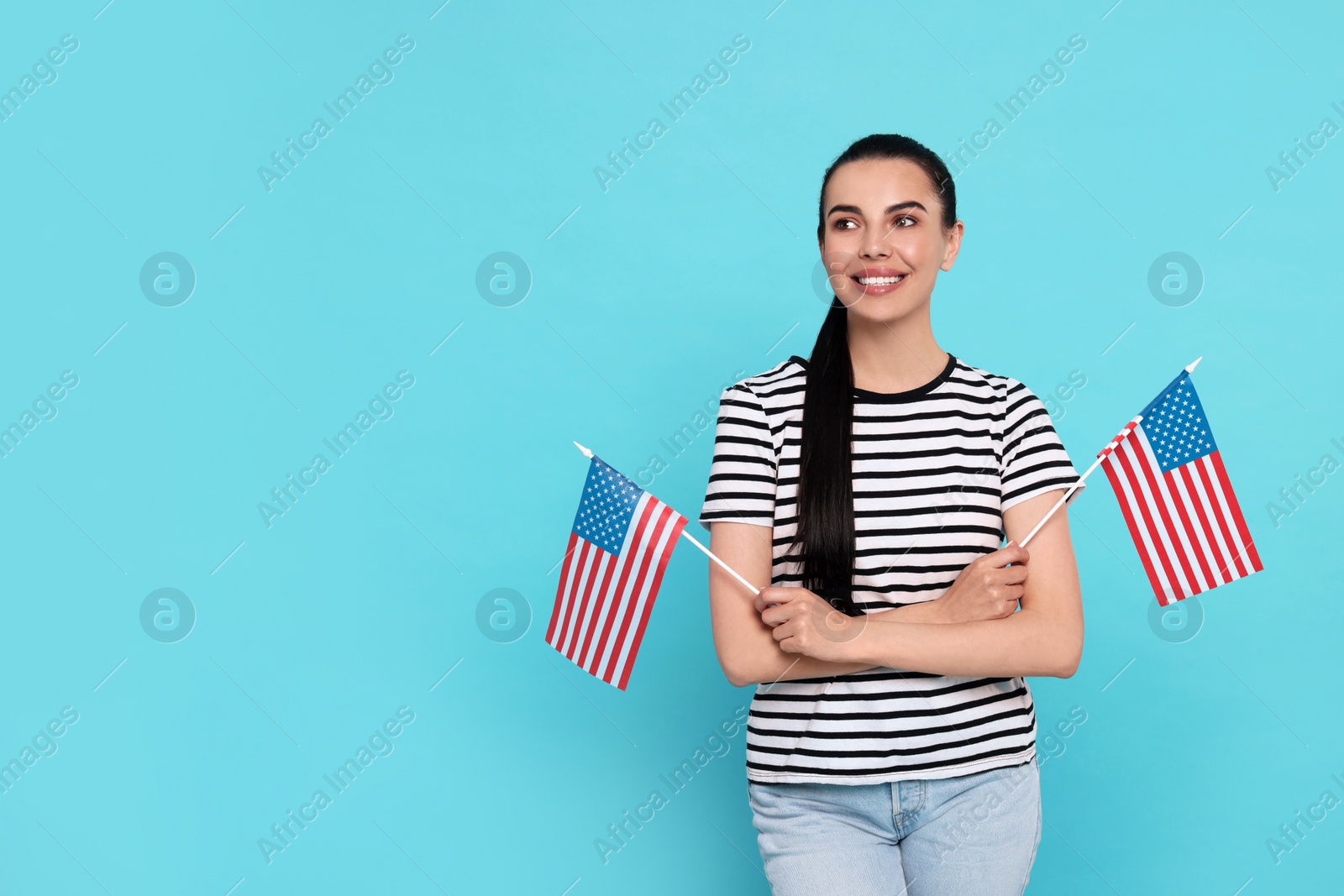 Photo of 4th of July - Independence Day of USA. Happy woman with American flags on light blue background, space for text