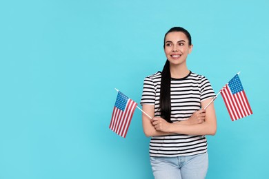 4th of July - Independence Day of USA. Happy woman with American flags on light blue background, space for text