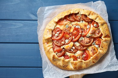 Photo of Tasty galette with tomato and cheese (Caprese galette) on blue wooden table, top view. Space for text