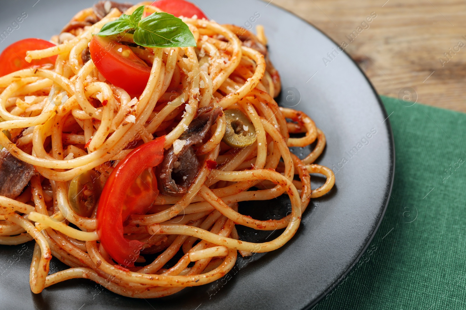 Photo of Delicious pasta with anchovies, tomatoes and olives on table, closeup