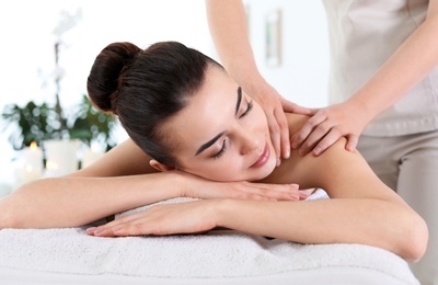 Photo of Young woman receiving massage in spa salon