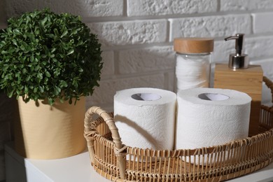 Photo of Toilet paper rolls, floral decor, dispenser and cotton pads on table indoors