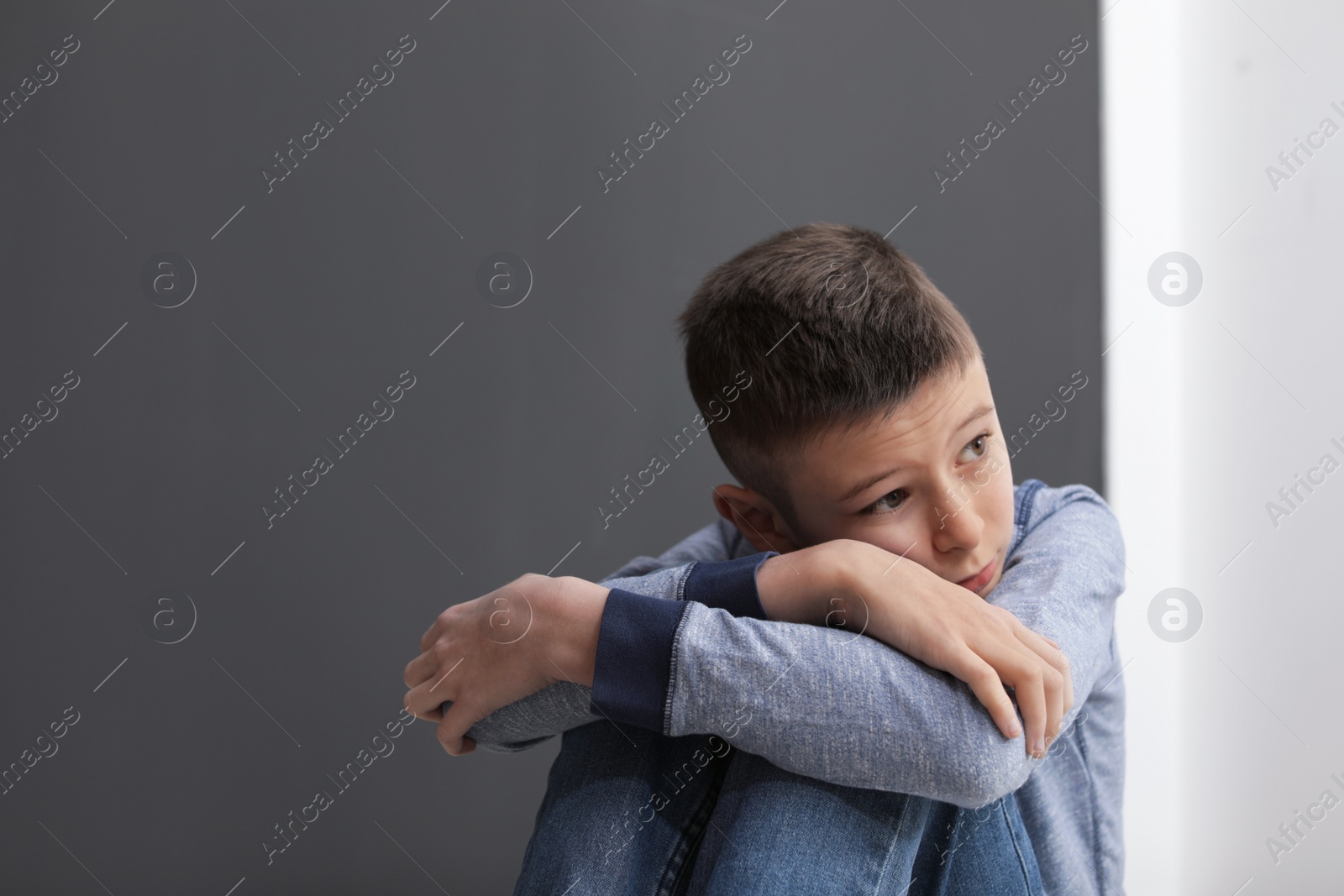 Photo of Upset preteen boy sitting indoors. Space for text