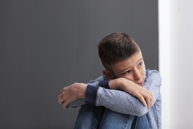 Photo of Upset preteen boy sitting indoors. Space for text