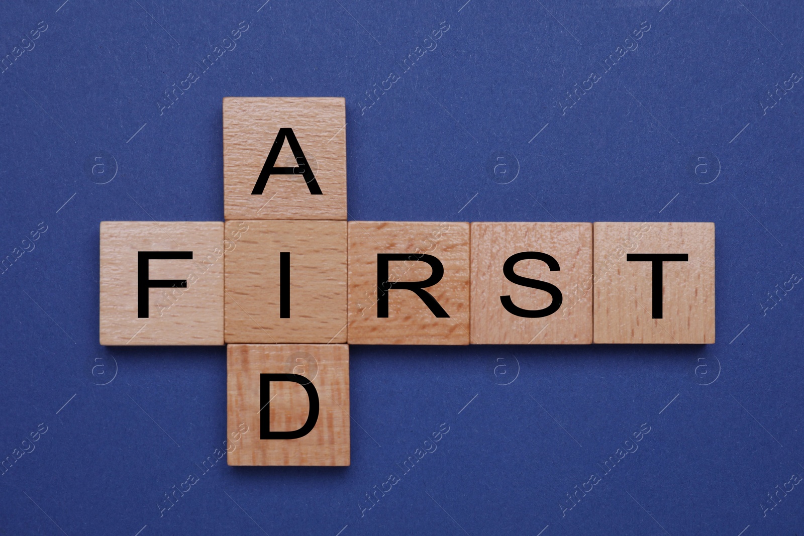 Photo of Words First Aid made of wooden cubes on blue background, top view