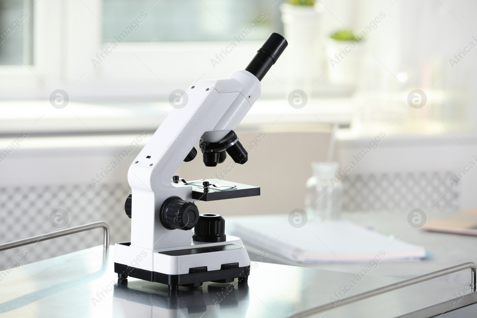 Photo of Modern medical microscope on metal table in laboratory