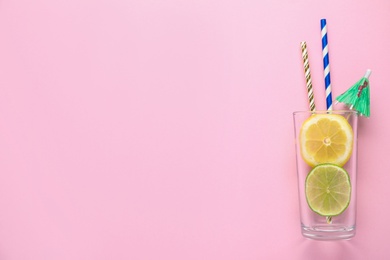 Photo of Creative image of summer cocktail made with citrus slices, straws and umbrella in glass on color background, top view. Space for text