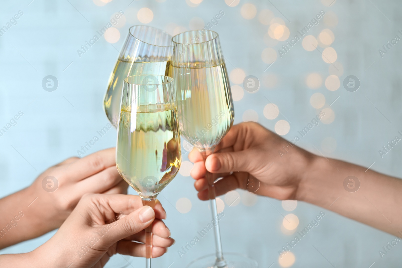 Photo of People clinking glasses of champagne against blurred lights, closeup