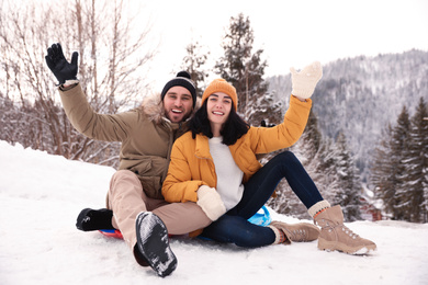 Photo of Young couple with snow sleds outdoors. Winter vacation