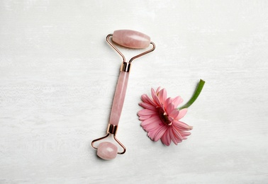 Photo of Natural face roller and flower on light background, flat lay