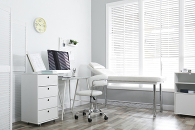 Modern medical office interior with computer and examination table