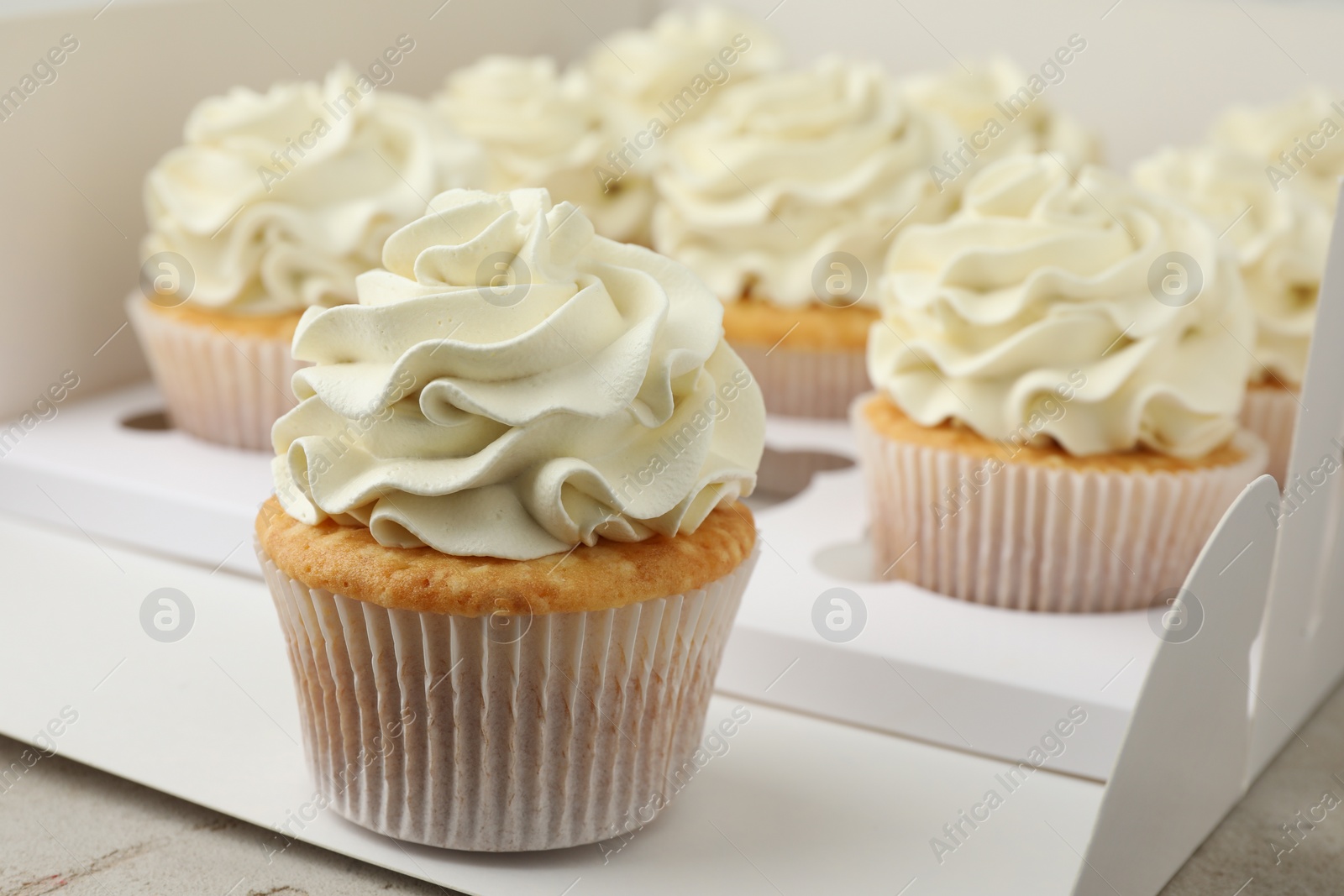 Photo of Tasty cupcakes with vanilla cream in box, closeup