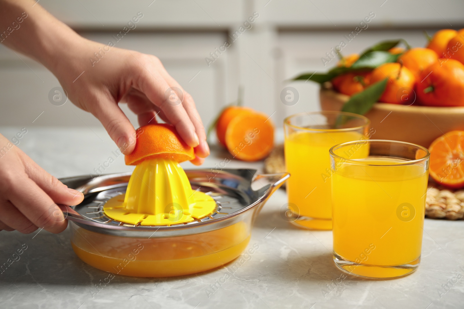 Photo of Woman making fresh tangerine juice indoors, closeup