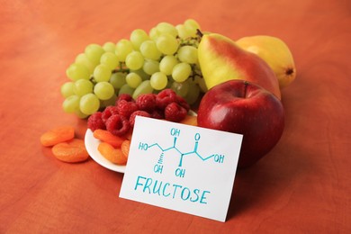 Photo of Card with word Fructose, delicious ripe fruits, raspberries and dried apricots on wooden table