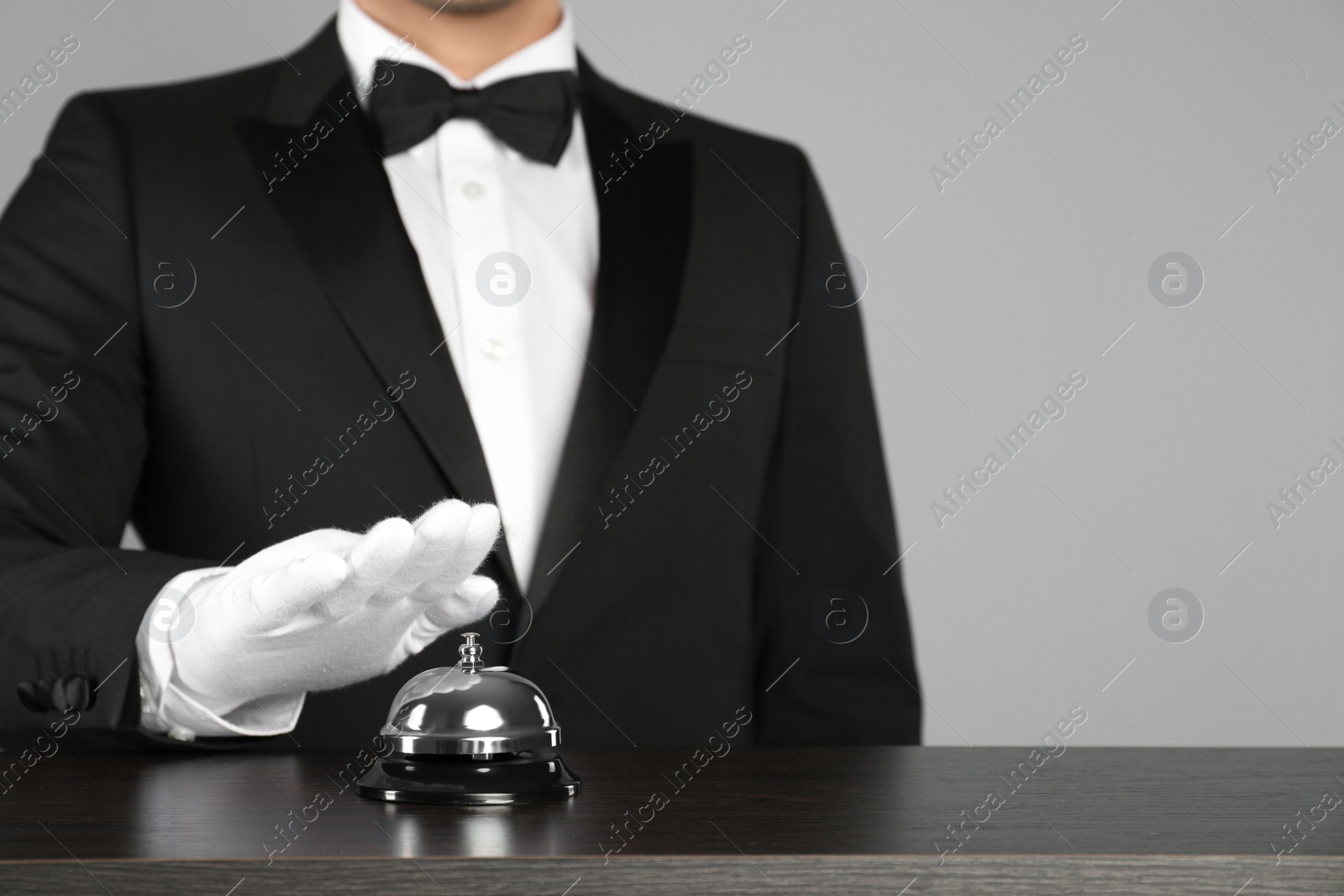 Photo of Butler ringing service bell at table, closeup. Space for text