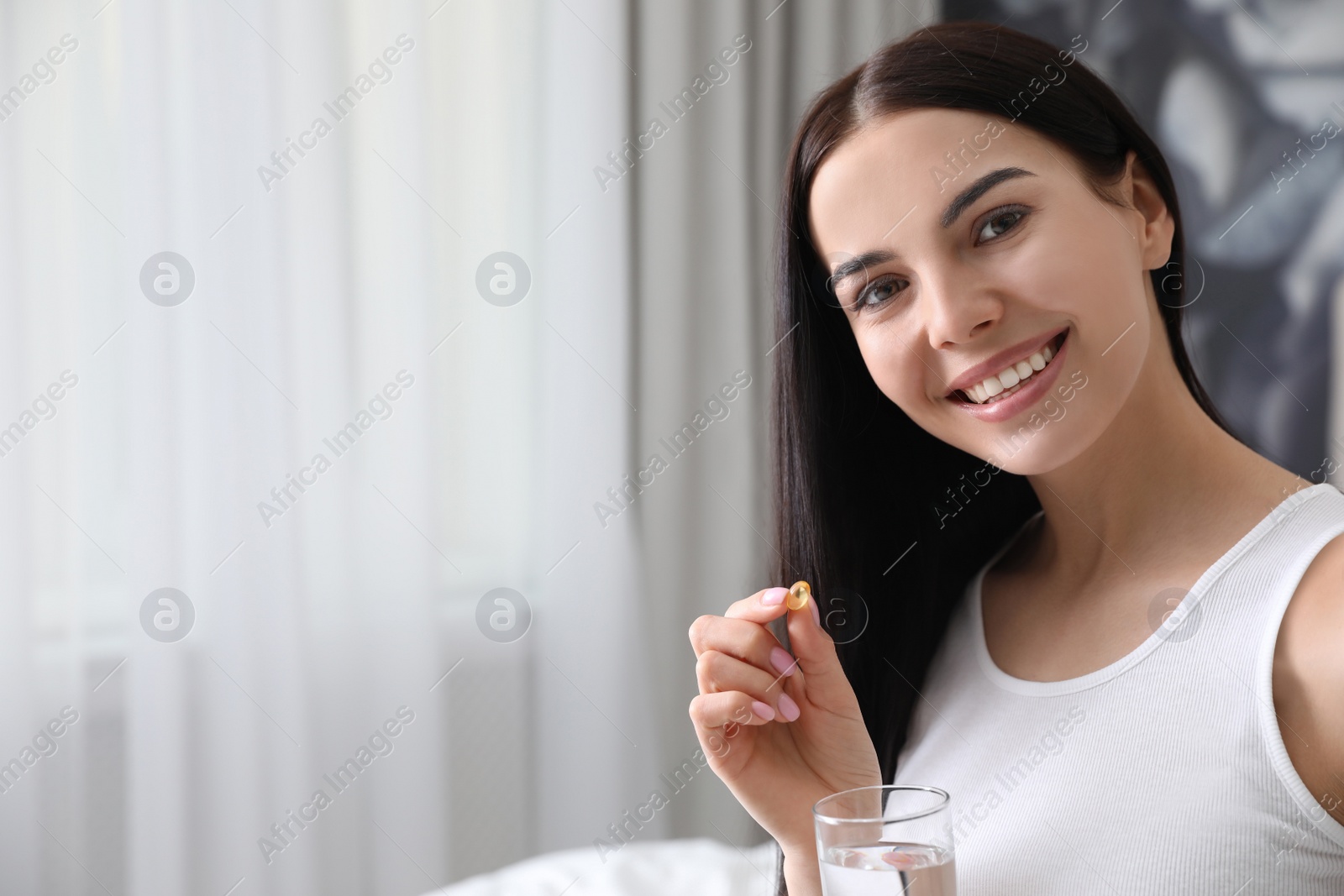 Photo of Woman with vitamin capsule indoors. Space for text