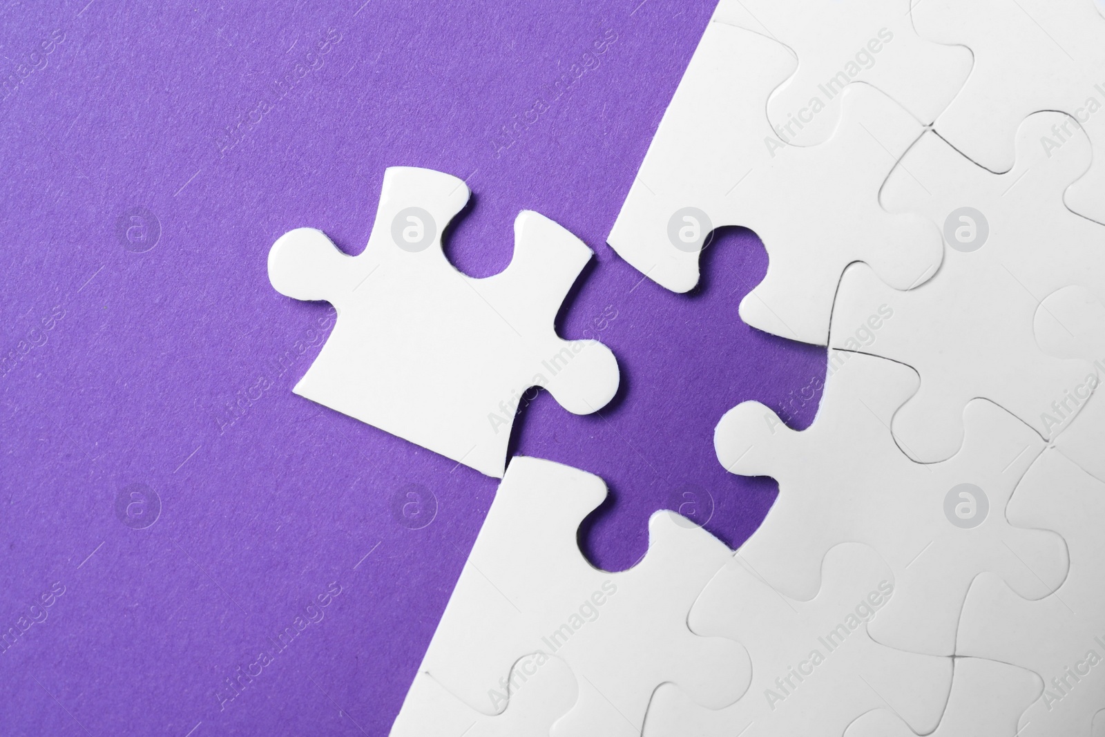 Photo of White puzzle with unfitting piece on purple background, flat lay