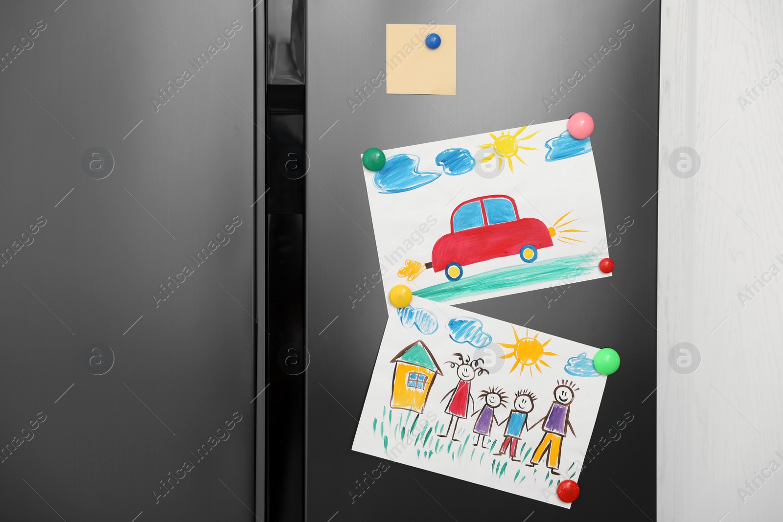 Photo of Modern refrigerator with child's drawings and magnets