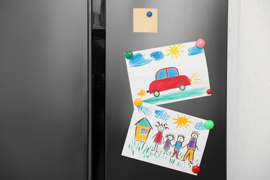 Photo of Modern refrigerator with child's drawings and magnets