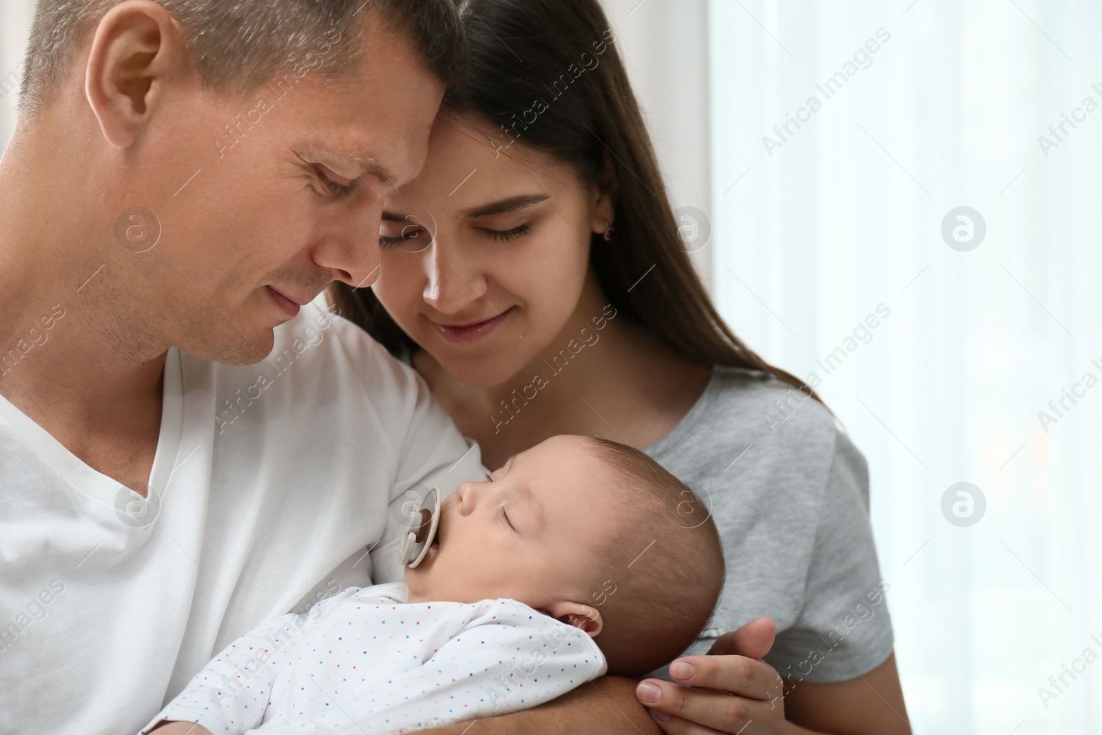 Photo of Happy family with their cute sleeping baby indoors