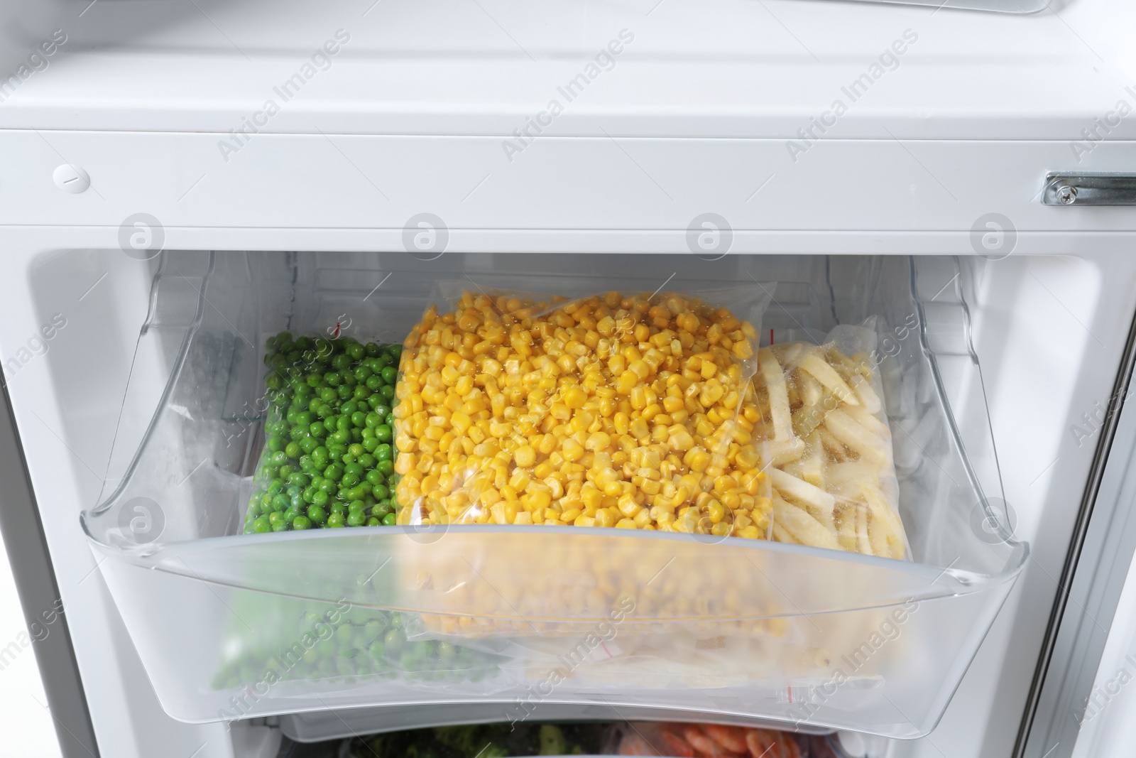 Photo of Plastic bags with frozen vegetables in refrigerator, closeup