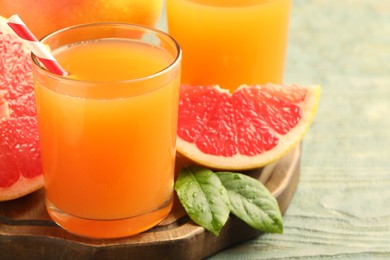 Glasses of delicious grapefruit juice on wooden table, closeup