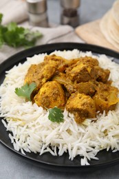 Photo of Delicious chicken curry with rice on grey table, closeup