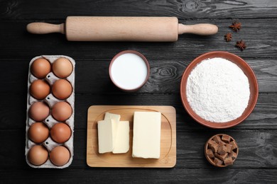 Cooking utensils and ingredients on black wooden table, flat lay