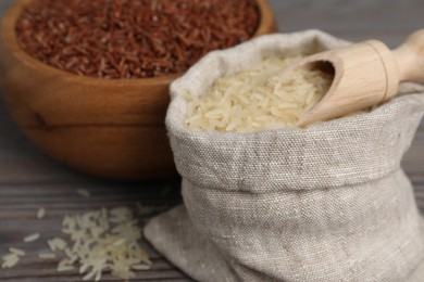 Photo of Bag and bowl with different sorts of rice on wooden table, closeup