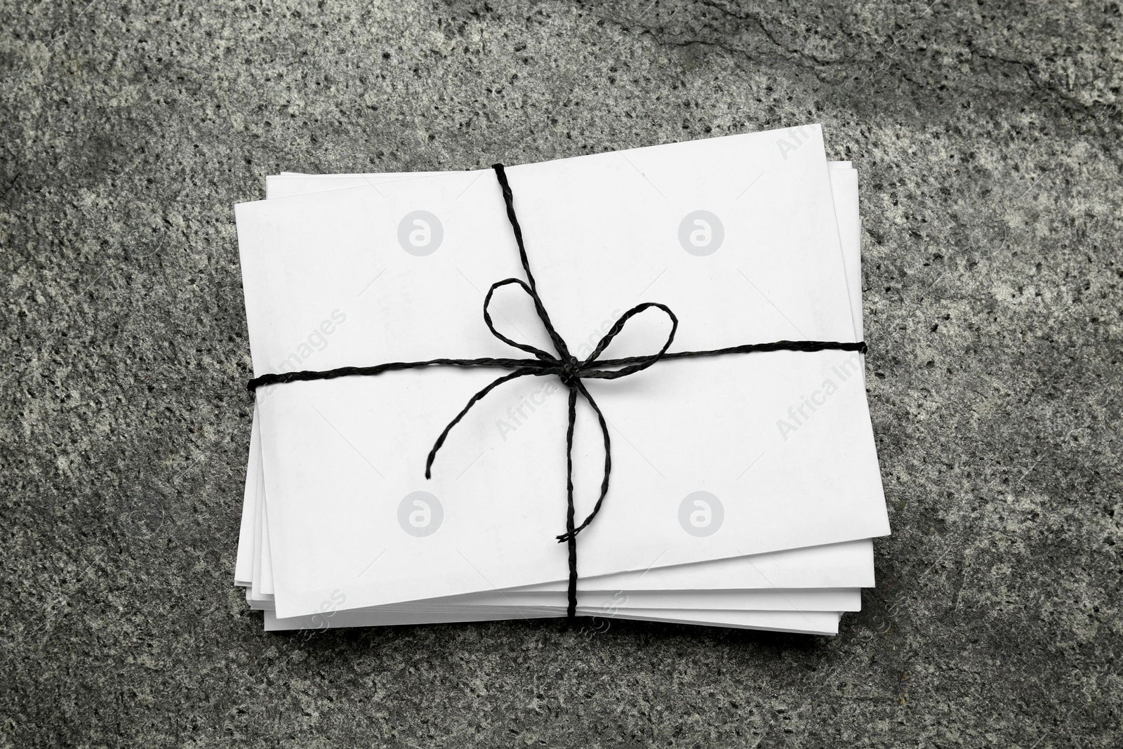 Photo of Stack of letters tied with string on grey table, top view