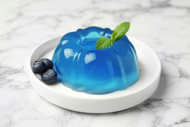 Photo of Plate of delicious blue jelly with berries on marble background