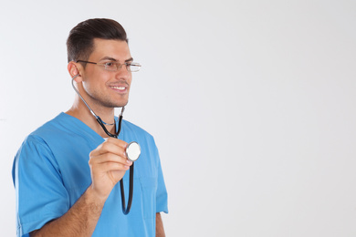 Doctor with stethoscope on light grey background. Space for text