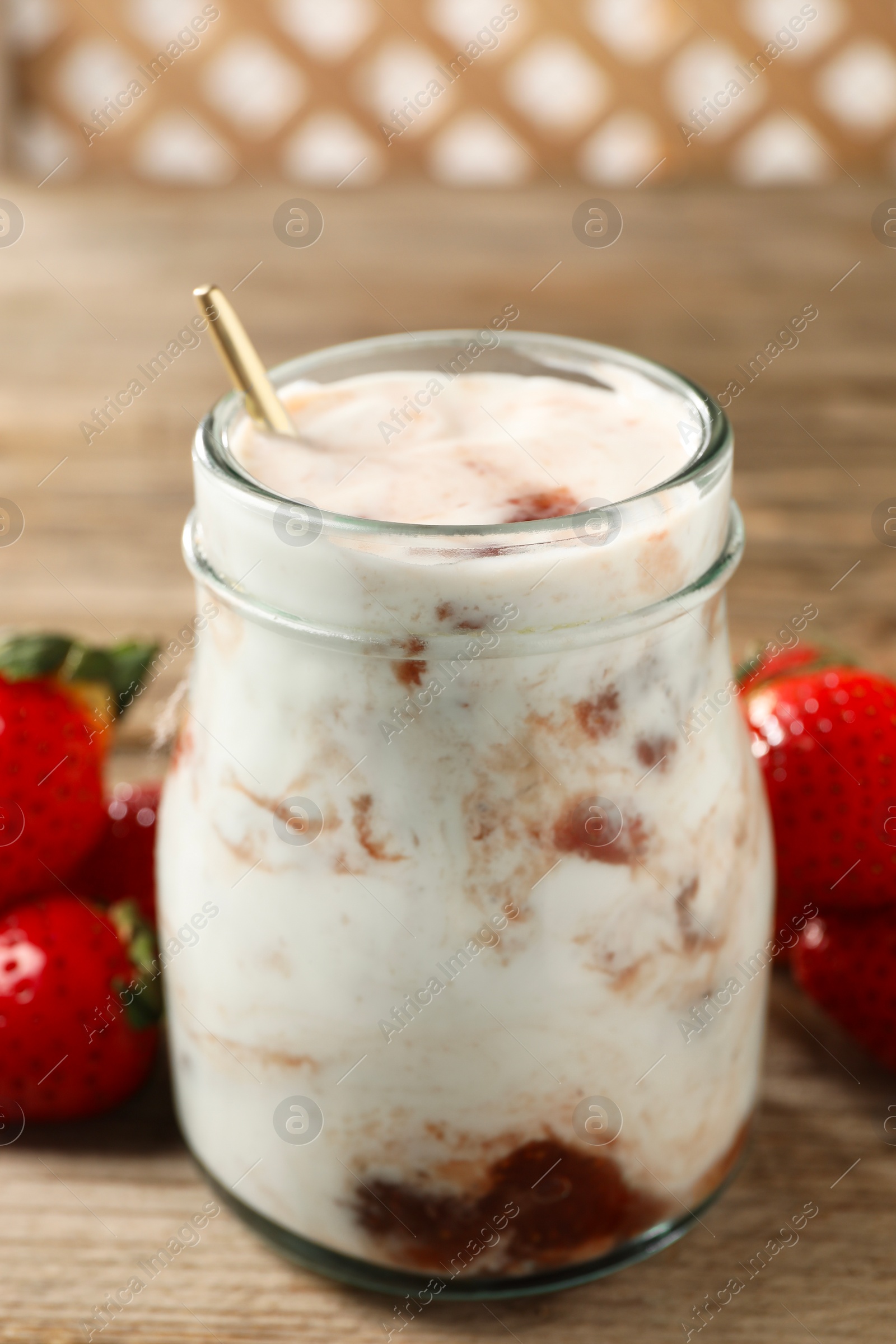 Photo of Tasty yoghurt with jam and strawberries on wooden table, closeup