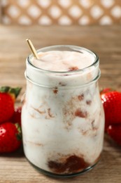 Photo of Tasty yoghurt with jam and strawberries on wooden table, closeup