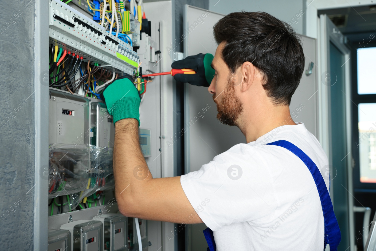 Photo of Electrician repairing fuse box with screwdriver indoors