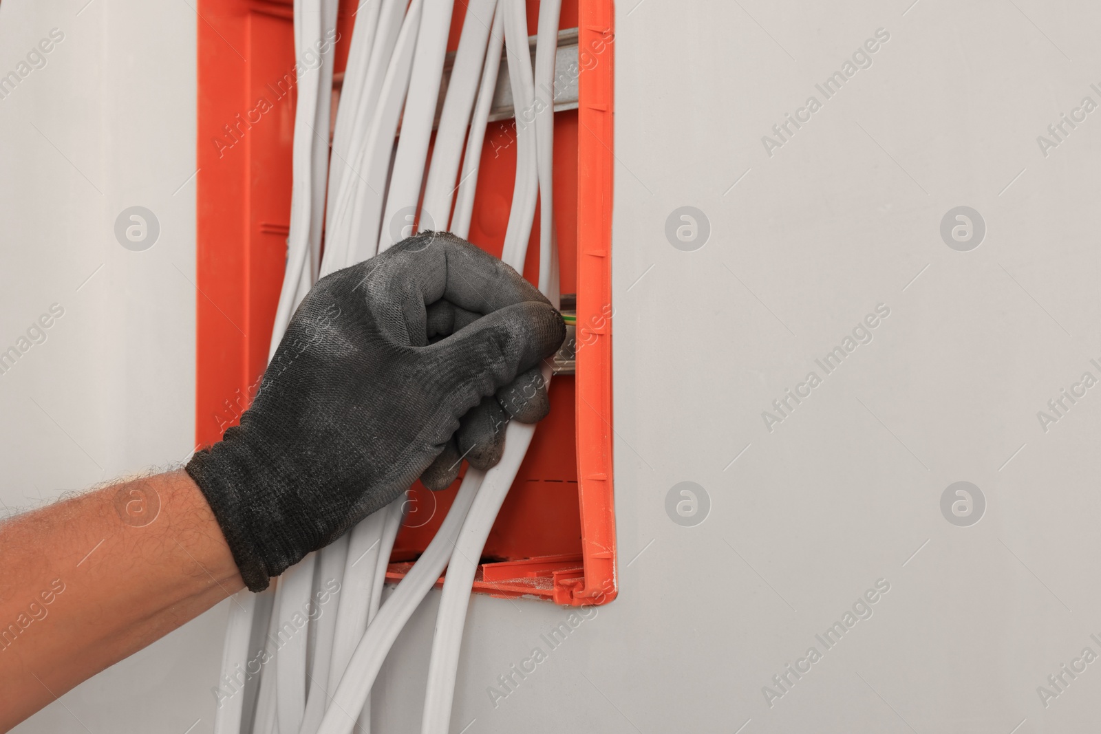 Photo of Electrician installing switchboard indoors, closeup with space for text. Installation of electrical wiring