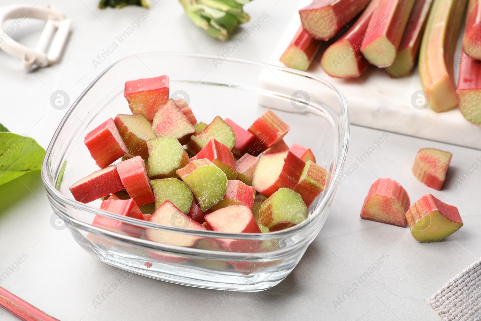 Photo of Whole and cut rhubarb stalks on white table