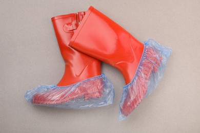 Photo of Rubber boots in shoe covers on grey background, top view