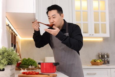 Man tasting dish after cooking in kitchen