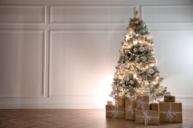 Beautiful decorated Christmas tree and gifts indoors. Space for text