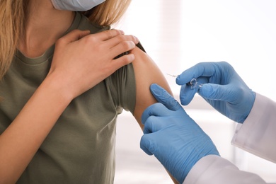 Photo of Doctor vaccinating young woman against Covid-19 in clinic, closeup