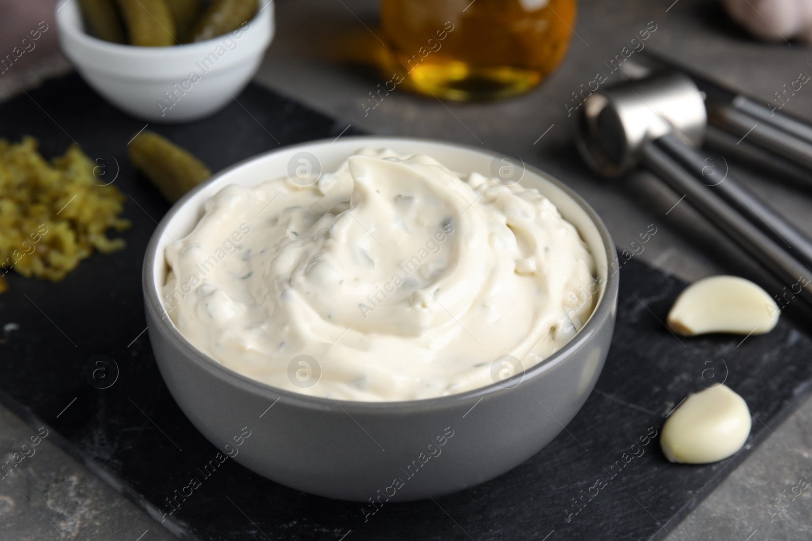 Photo of Tasty tartar sauce and ingredients on grey table, closeup