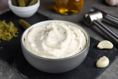 Photo of Tasty tartar sauce and ingredients on grey table, closeup