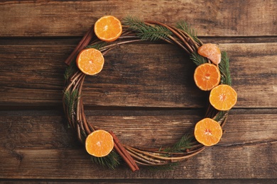 Decorative wreath with tangerines, fir tree branches and spices on wooden table, top view