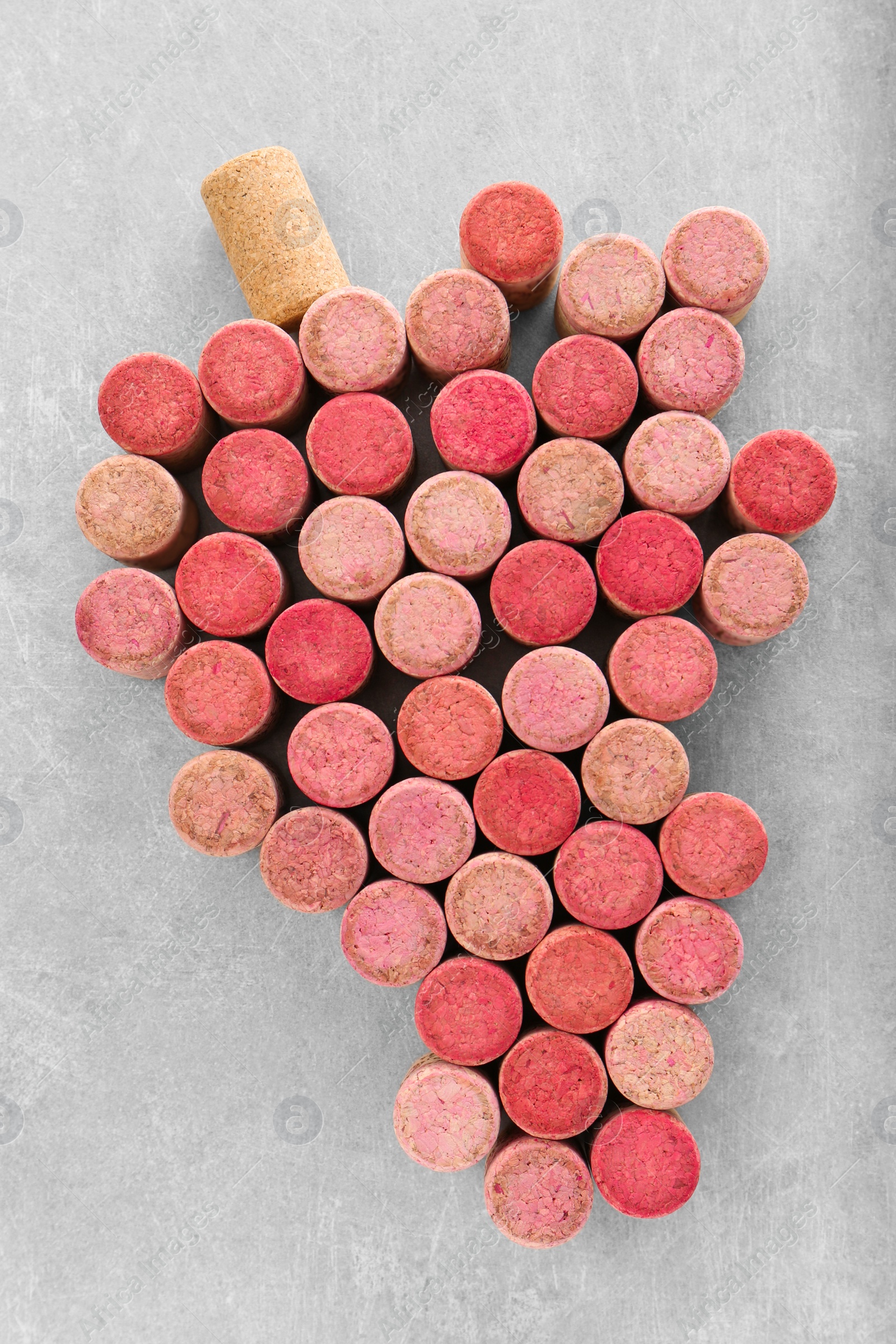 Photo of Grape made of wine bottle corks on grey table, top view